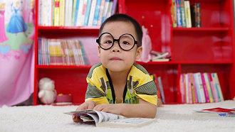 boy with glasses with book case in background